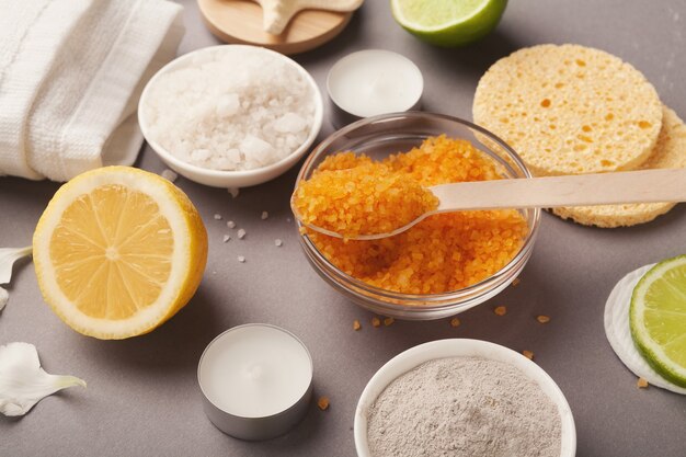 Фон спа. Натуральная морская соль с эфирным маслом лимона и различными косметологическими продуктами на сером столе. Салон или домашний кузов и кожа автомобиля