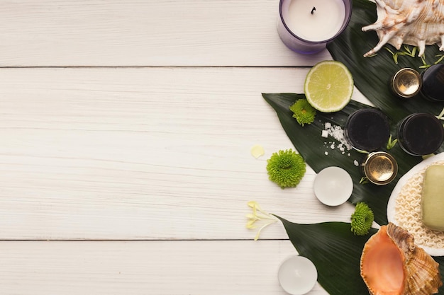 스파 배경입니다. 흰색 탁자에 있는 큰 녹색 잎에 천연 스킨케어 제품. 살롱 또는 홈 바디 및 스킨 케어, 복사 공간, 평면도