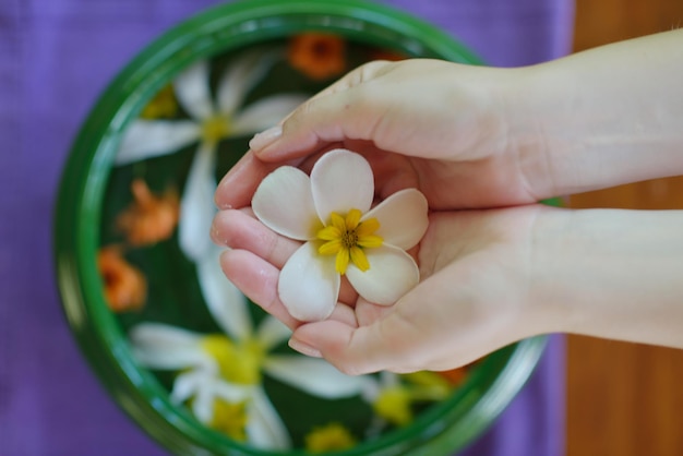 スパと美しさの女性の手と水の中の花