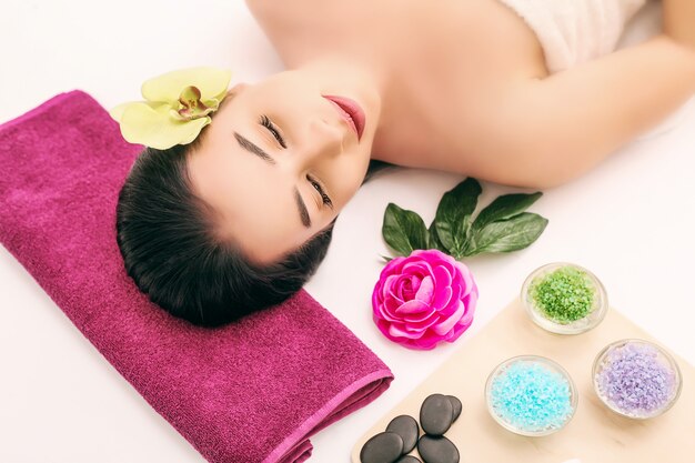 Spa, beauty, people and body care , beautiful woman getting face treatment over holidays light 