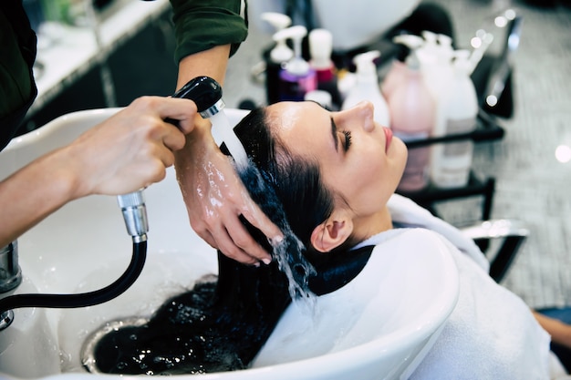 Spa behandelingen. Bovenaanzicht van de handen van de kapper die het haar van haar klant in de salon wast vóór het hairstylingproces.