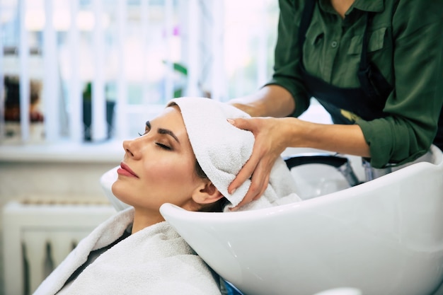 Foto spa behandelingen. bovenaanzicht van de handen van de kapper die het haar van haar klant in de salon wast vóór het hairstylingproces.