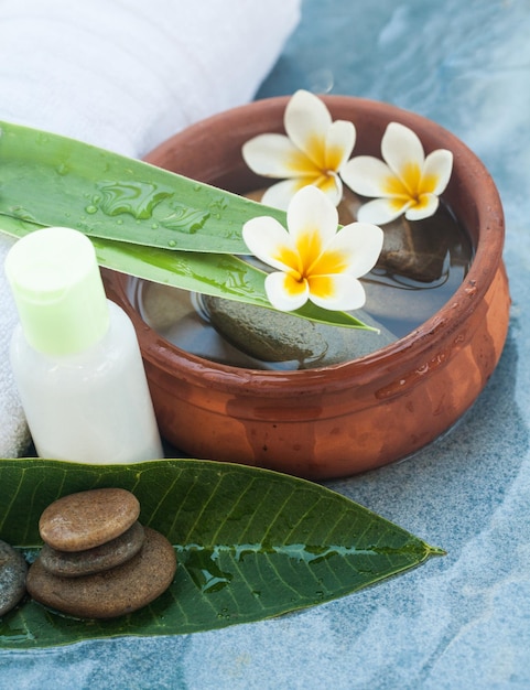 Spa bloemen en stenen en bladeren en oliefles voor massagebehandeling op blauwe achtergrond