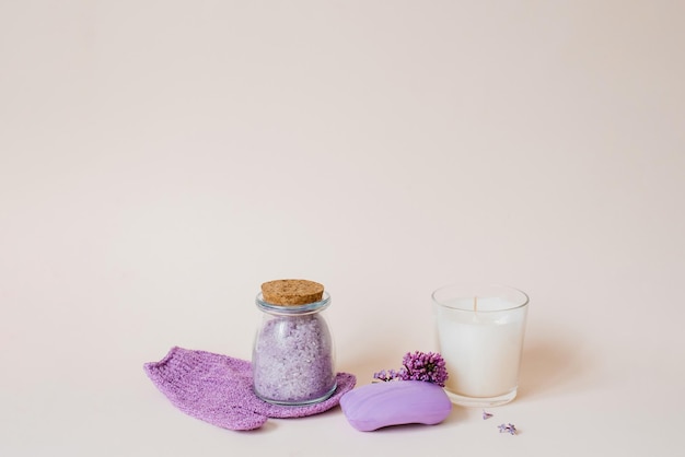 Photo spa care with natural soap sea salt washcloth glove for body care lilac flowers and a candle on a light background with copy space