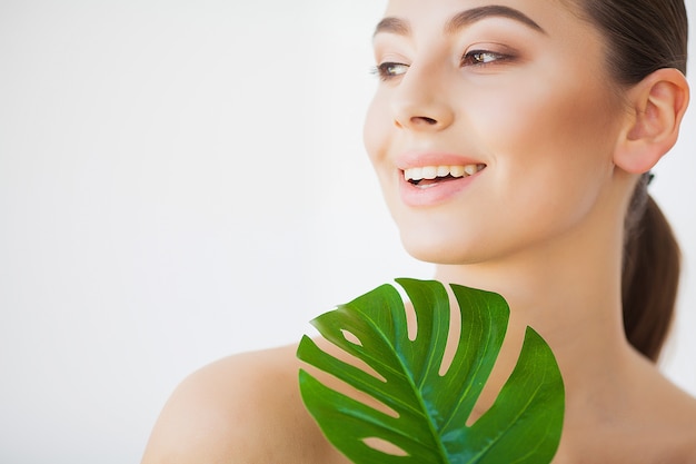 Spa care. Young pretty brunette woman with big green leaf