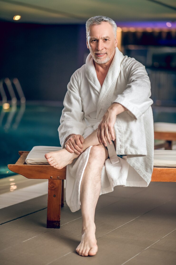 Photo spa center. a gray-haired bearded man in a white bath robe in spa center