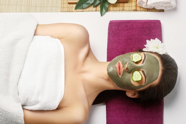 spa clay mask woman with clay facial mask and cucumbers on eye