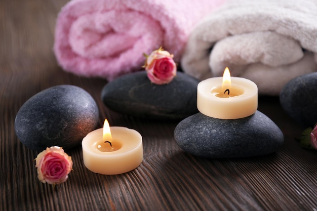 Spa composition of candles flowers and stones on brown wooden background