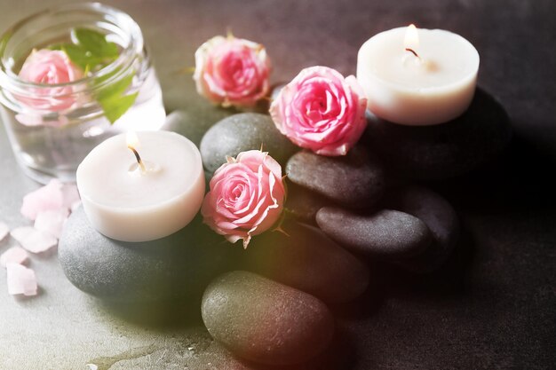 Photo spa composition of candles stones and flowers on grey background