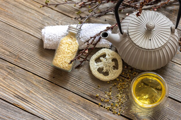 Photo spa composition in rustic style with kettle, tea and loofah on a wooden surface.