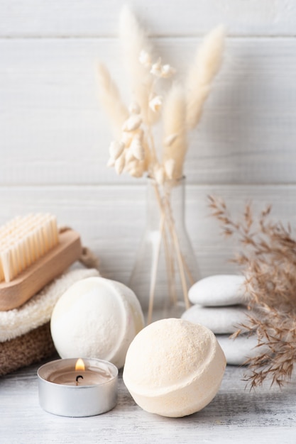 Spa composition with bath bombs and dry flowers on rustic table in monochrome style. Towel with candles and white pebbles. Hot stone massage therapy for one person. Beauty treatment and relax