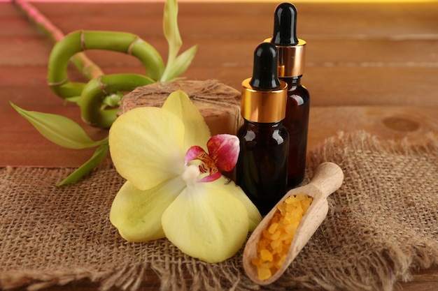 Spa composition with bottles of aromatic oils and bamboo on wooden background