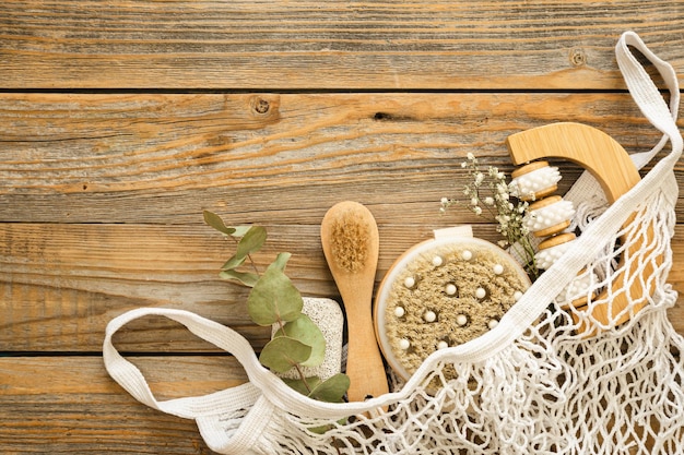 Foto composizione spa con spazzole per massaggi e articoli per l'igiene in una borsa della spesa in rete su un concetto di eco con vista dall'alto su fondo in legno