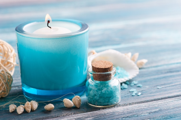 Spa composition with scented candle and sea salt on blue wooden background. Beauty treatment and relax with copy space
