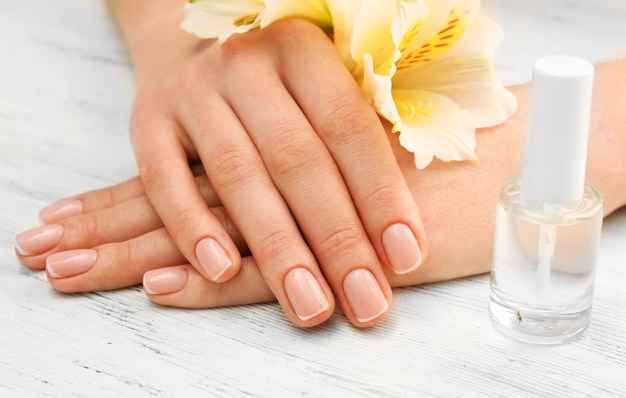 Spa concept Vrouw handen met mooie bloemen en nagellak op houten achtergrond close-up