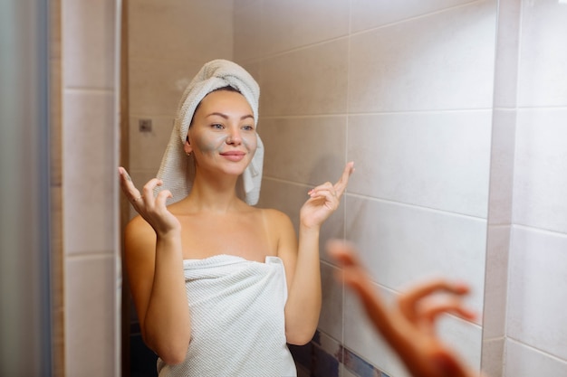 Spa en cosmetologie gezichtsverzorging thuis meisje in de badkamer brengt een crème gezichtsmasker aan