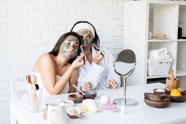 Spa- en wellness-concept. zelfzorg. twee mooie vrouwen die gezichtsmasker met plezier toepassen