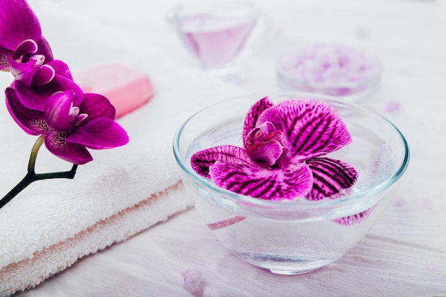 Prodotti essenziali per la spa, tra cui olio di sapone al sale e orchidea con cosmetici biologici per la cura del corpo dell'asciugamano