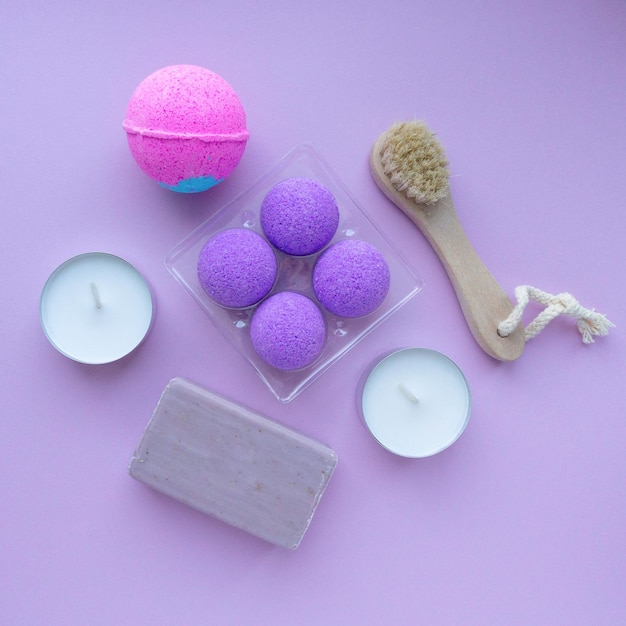 Spa flat lay. Bath bombs, soap and massage brush on purple background, top view
