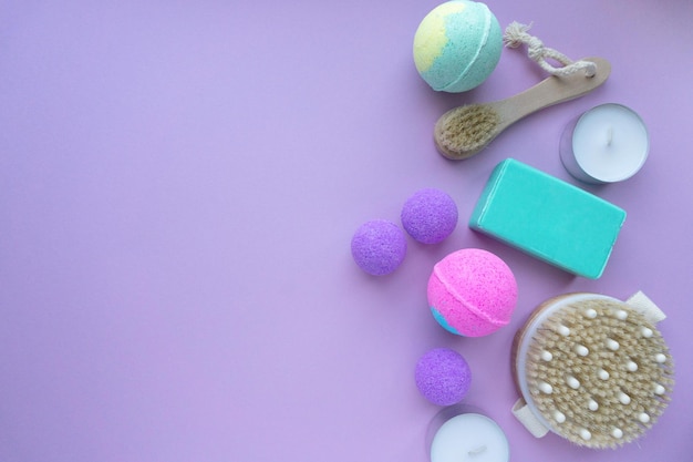 Spa flat lay. Bath bombs, soap and massage brushes on purple background, space for text.