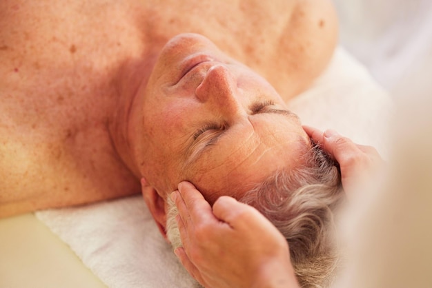 Spa head massage and senior man for luxury self care and muscle healing treatment for relaxation Health wellness and elderly male person on a retirement retreat for face therapy at natural salon