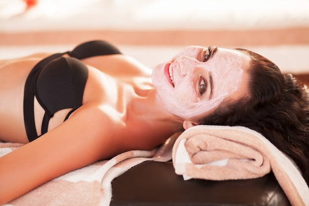 Maschera spa. la bella donna ottiene la maschera della stazione termale sulla spiaggia soleggiata nel salone della stazione termale all'aperto. alta qualità. cura della cicatrice.