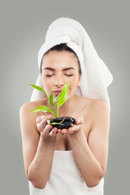 Spa Model Holding Green Bamboo and Black Stones Young Spa Woman with Healthy Skin and White Towel Massage Bodycare and Spa Beauty Concept