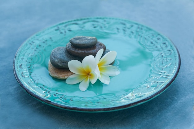 Spa objects and stones in plate on blue background