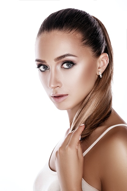 Spa portrait of a beautiful tanned brunette woman with perfect makeup on white background