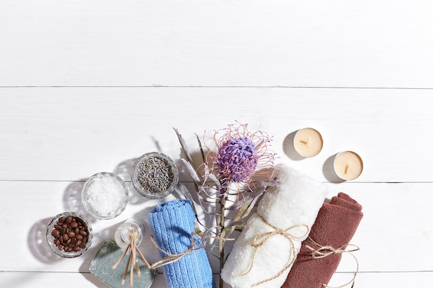 Spa producten badzout droge bloemen lavendel zeep kaarsen en handdoek plat lag op witte houten backgro