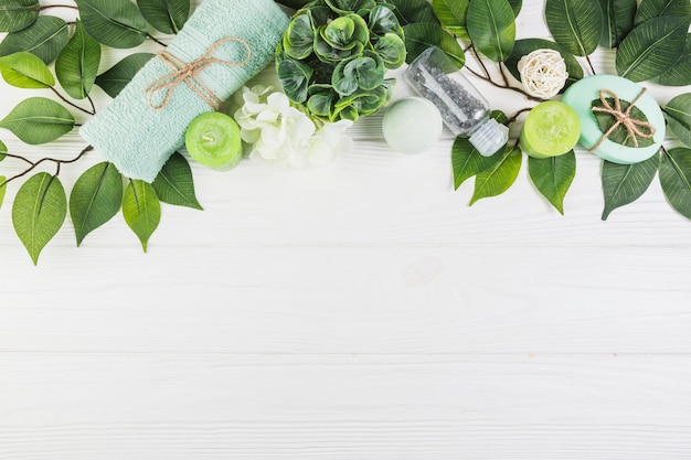 Spa products decorated with green leaves on wooden surface