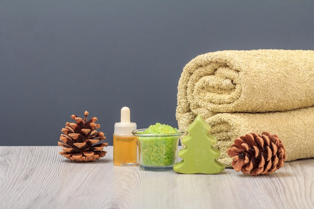 Spa-samenstelling met een zachte badstof handdoek, een fles met aromatische olie, een kom met zeezout en kegels op de grijze achtergrond