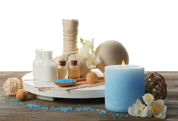 Foto spa samenstelling met zeezout in een kom massage ballen en bloemen op houten tafel tegen witte achtergrond