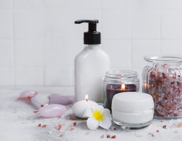 Spa set essential oil massage salt candle and frangipani flowers on gray concrete background