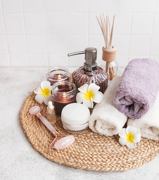 Spa set, essential oil, massage salt, candle and  frangipani flowers on gray concrete background