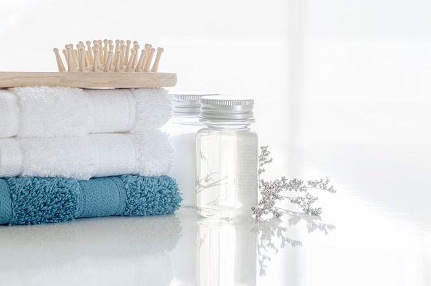 Spa set with stack of clean towels, oil bottle, wooden comb and flower 