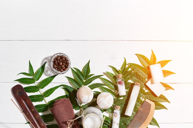 Spa set with towel and soap on white wooden background with green leaves sun flare