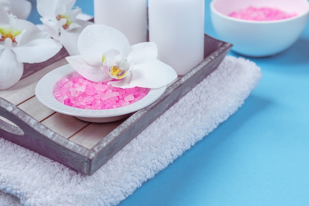 Spa setting still life with orchid flower , candle, soap and towels on blue background