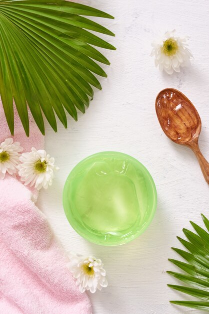 Spa setting with cosmetic gel, leaves on white table background