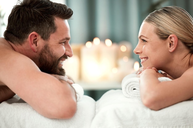 Spa smile and couple on massage bed table for luxury messaging relax and zen on holiday in hotel resort Wellness happy man and woman looking into eyes in body care treatment or vacation together