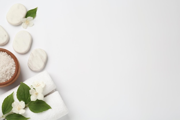 Spa stenen mooie jasmijn bloemen zeezout en handdoeken op witte achtergrond plat leggen Ruimte voor tekst
