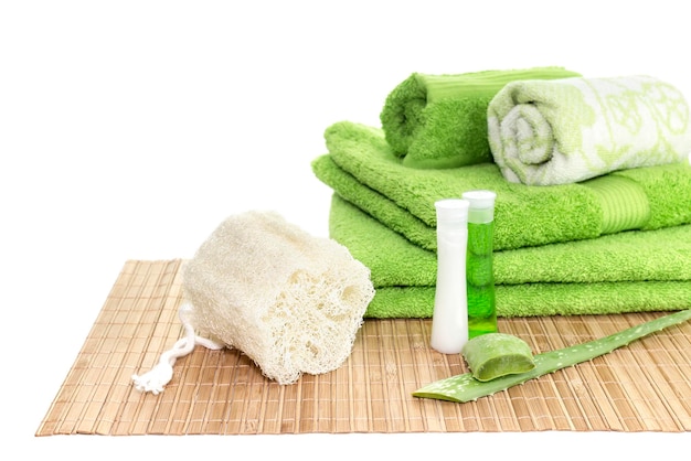 Spa still life Personal hygiene items green towels natural sponge and aloe leaves on a table closeup