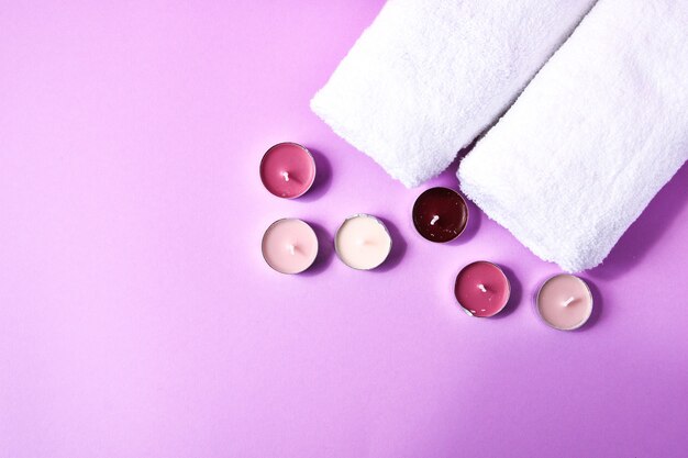 Spa still life treatment with candles and towels on pink background, copy space for text