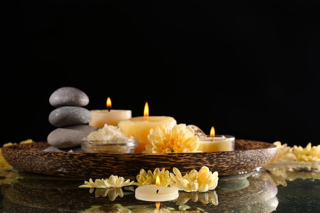 Spa still life with flowers and candlelight on black background