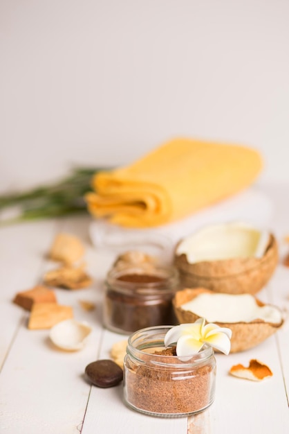 Spa still life with fresh coconut and body care products on white wooden table. Relaxation, spa treatment, skin care, beauty concept. Copy space.