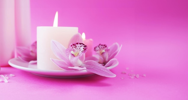 Spa still life with orchid flowers and candles on pink background relaxation atmosphere