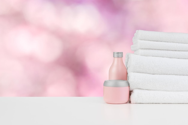 Spa still life with towels and skincare cosmetics against blurred background