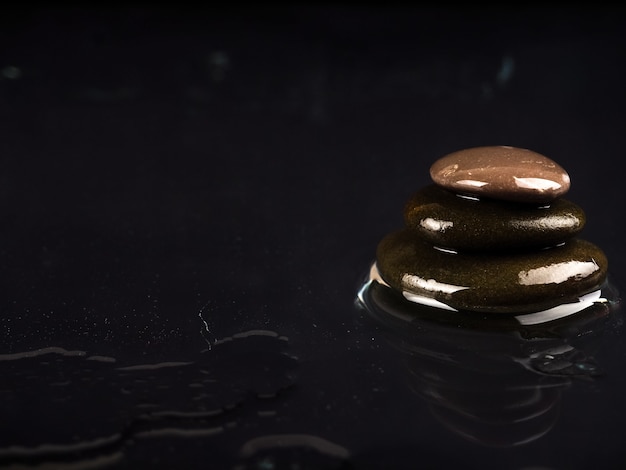 Spa Stones. black shiny zen stones with water drops over black wall