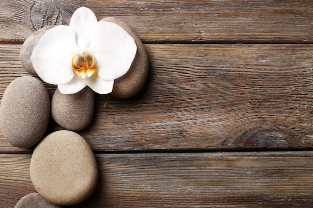 Spa stones and orchid flower on wooden background