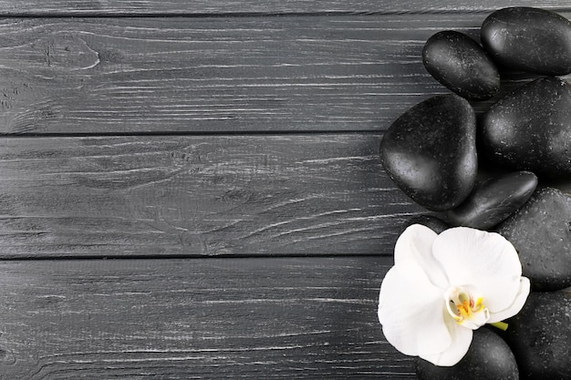 Spa stones and orchid flower on wooden background